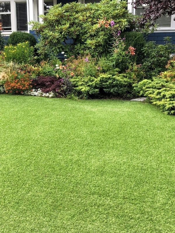 Beautiful artificial turf in front of a flowerbed. 