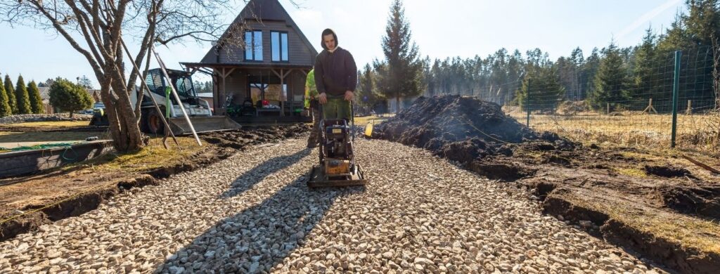 A landscaper is installing a gravel driveway.