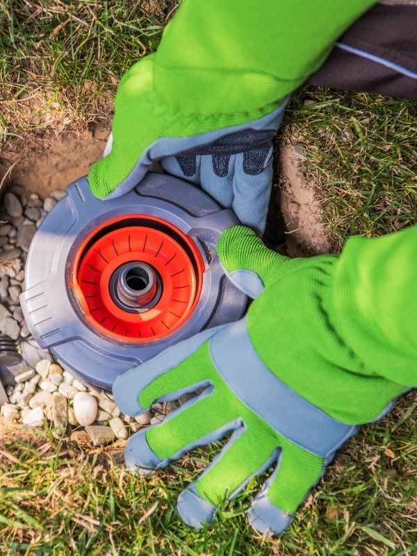 A person fixing a sprinkler head.